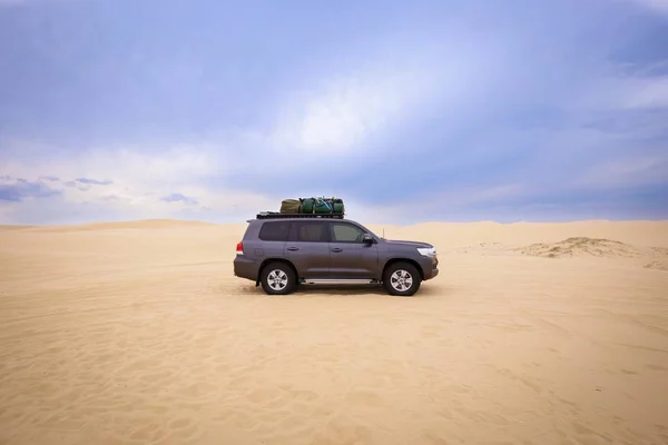 Coche con equipaje encima en el desierto bajo un cielo nublado durante el día —  Fotos de Stock