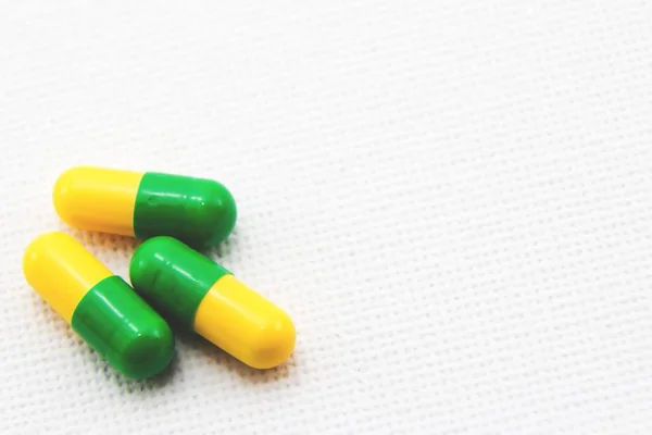 Hoge hoek close-up van een drie gele en groene capsules op een wit oppervlak — Stockfoto