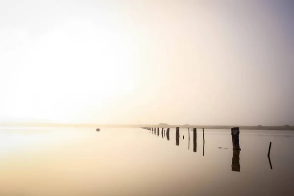 Mer avec des bois réfléchissant sur l'eau entourée de collines pendant le coucher du soleil — Photo