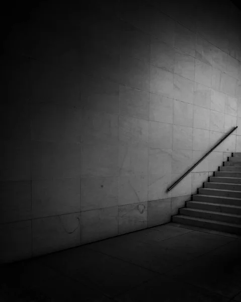 Függőleges szürkeárnyalatú felvétel egy lépcsőről a szürke kőfal mellett — Stock Fotó