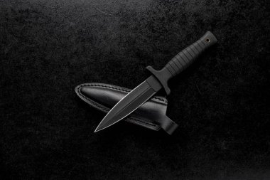 Closeup shot of a fixed military knife with a black holder and a case on a black background clipart