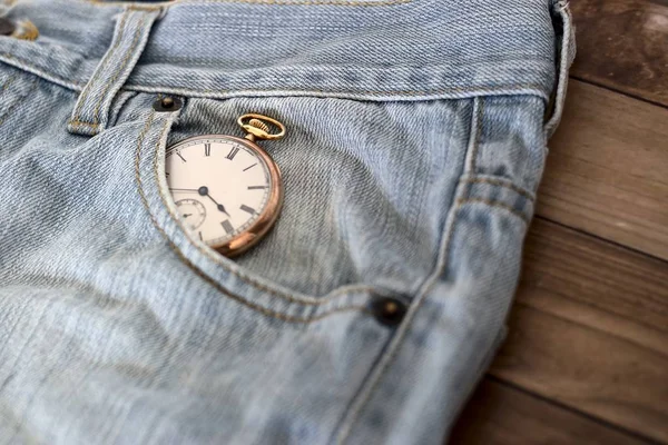 Zegar w kieszeni dżinsów na drewnianej powierzchni - koncepcja zarządzania czasem — Zdjęcie stockowe