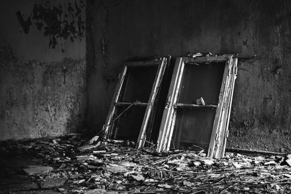 Grayscale tiro de caixilhos de janela colocados em um piso bagunçado em uma casa velha — Fotografia de Stock