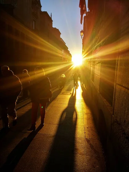 Sun shining through the people and the buildings during a sunset — Stock Photo, Image