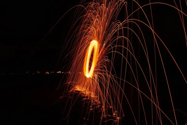 Glödande ljus sträcker ut sina gnistor i luften som det snurrar snabbt — Stockfoto