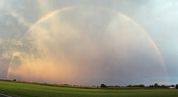 Hermoso disparo de un arco iris en un campo verde con un cielo nublado en el fondo. —  Fotos de Stock