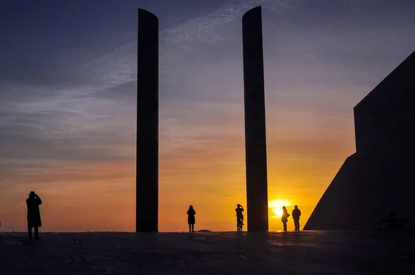 Silhouettes de personnes à proximité des immeubles de grande hauteur pendant le beau coucher de soleil dans la soirée — Photo