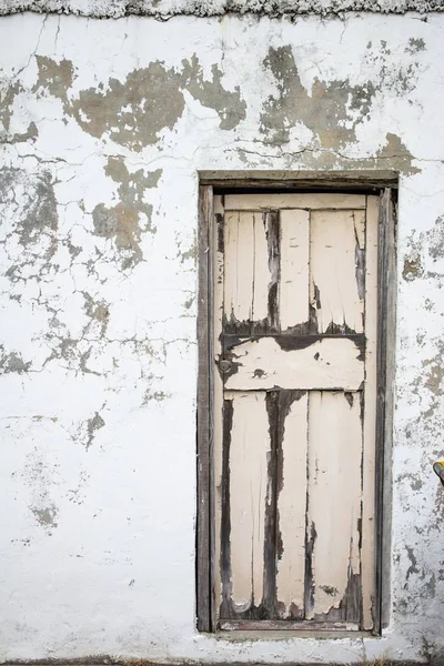 Vertikal bild av en gammal vittrad vägg med en trädörr — Stockfoto