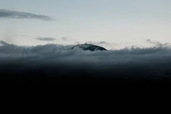 Uma Colina Coberta Nuvens Escuras Pesadas Sob Céu Pálido Durante — Fotografia de Stock