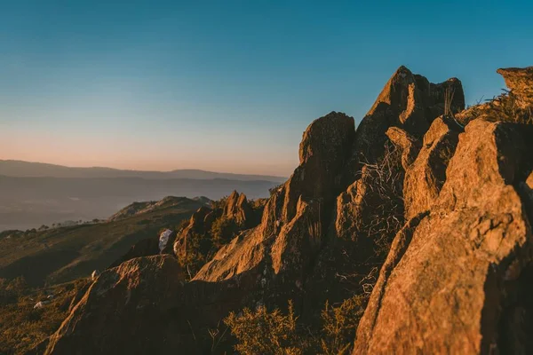 Wide angle shot of a cliff on a mountain under the sun and a clear blue sky — Stock Photo, Image