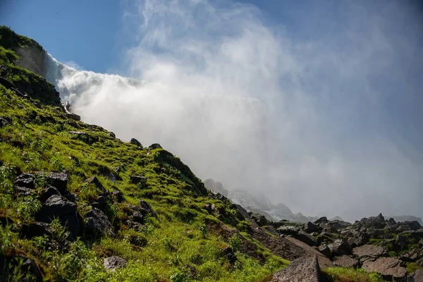 Niagara ile yosunlarla kaplı kayaların manzarası arka planda güneş ışığının altına düşüyor. — Stok fotoğraf