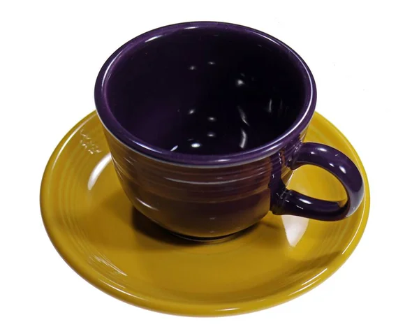 Egy üres, lila csészéről készült kép egy sötét sárga kis tányérba helyezve. — Stock Fotó