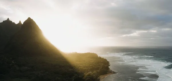 一张美丽的海滨陡峭的山的照片 背景是乌云密布的日落 — 图库照片