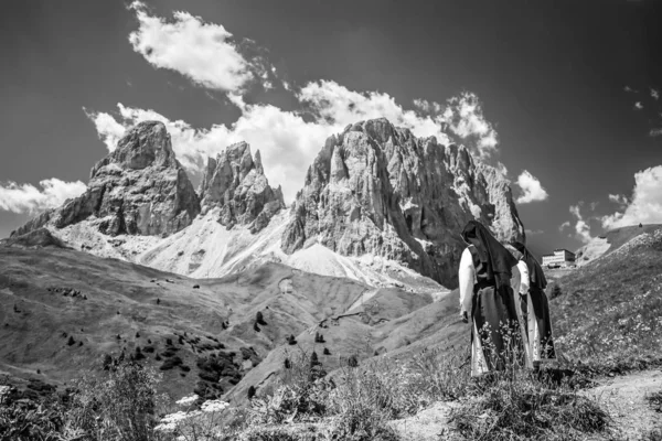 Scatto in scala di grigi di suore che scendono dalla collina con le montagne sullo sfondo — Foto Stock