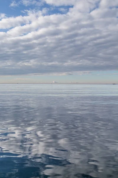 Prachtige opname van een wateroppervlak dat de witte bewolkte lucht weerspiegelt — Stockfoto