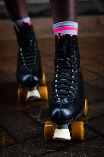 一个穿黑色轮滑鞋的女人在地板上的垂直镜头 — 图库照片