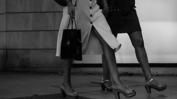 Серый снимок стильных дам, идущих на каблуках по улице — стоковое фото