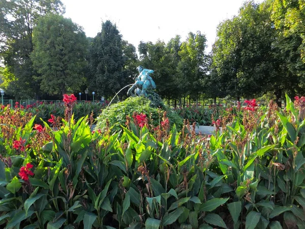 Ángulo amplio de tiro de una estatua rodeada de árboles, hierba y flores. — Foto de Stock