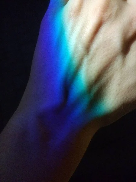 Closeup shot of several colors reflected on someone's hand — Stock Photo, Image