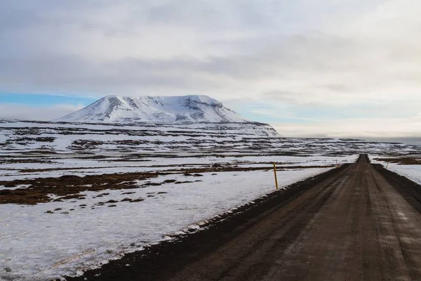 Eine Straße Umgeben Von Feld Und Schneebedeckten Felsen Unter Wolkenverhangenem — Stockfoto