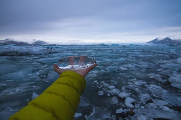 El hielo de la mano con un mar congelado bajo un cielo nublado en Islandia en el fondo. — Foto de Stock