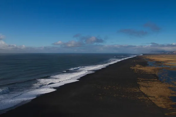 Plaża otoczona morzem ze wzgórzami na tle chmurnego nieba na Islandii — Zdjęcie stockowe
