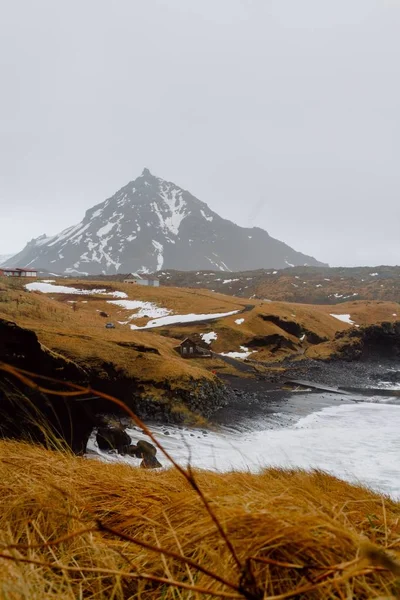 İzlanda 'da kar ve yeşillikle kaplı tepelerle çevrili bir nehrin dikey resmi. — Stok fotoğraf