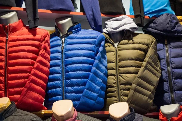 Крупный план пальто разных цветов на манекенах в магазине — стоковое фото