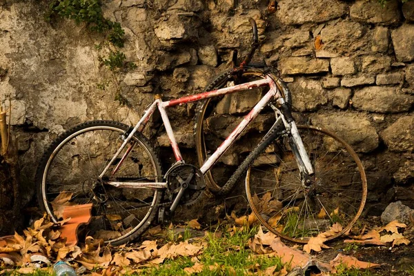 Gros plan d'un vélo cassé devant un mur de pierre — Photo