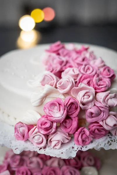 A vertical closeup shot of a cake with beautiful pink roses on the surface