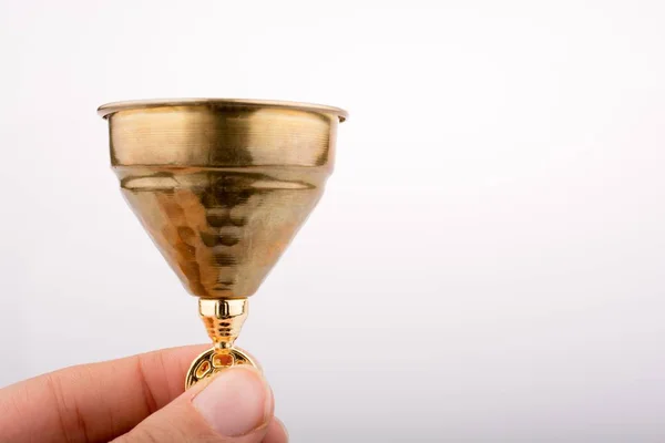 白い背景の金色の瓶を持つ人間の指の孤立したショット — ストック写真