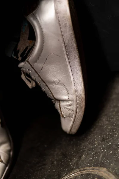 Vertikal närbild skott av en vit sneaker på asfalten marken — Stockfoto