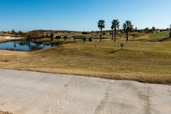 Campo da golf con percorso golf cart, palme e un laghetto sul lato in Spagna — Foto Stock