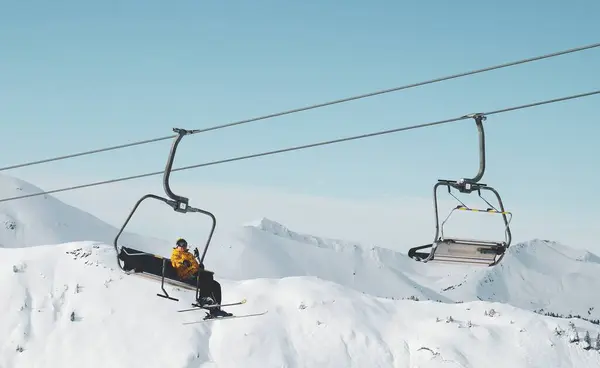 Lage hoek opname van een persoon zittend op een kabelbaan in een besneeuwde berg — Stockfoto