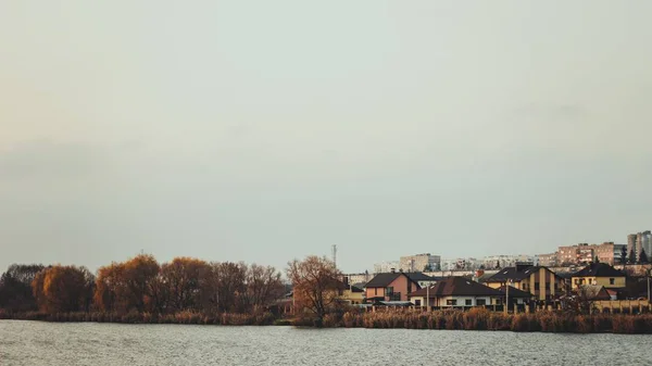 秋の木々や家屋に囲まれた澄んだ湖 — ストック写真