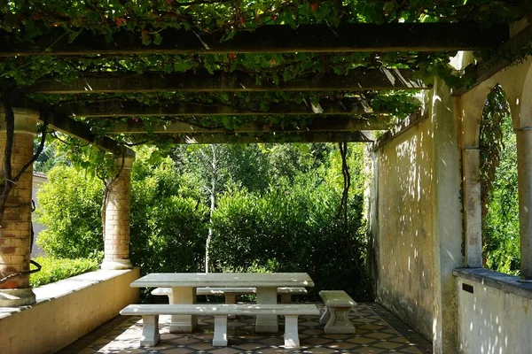 Beautiful shot of a wooden pavilion with a stone bench in a garden — Stock Photo, Image