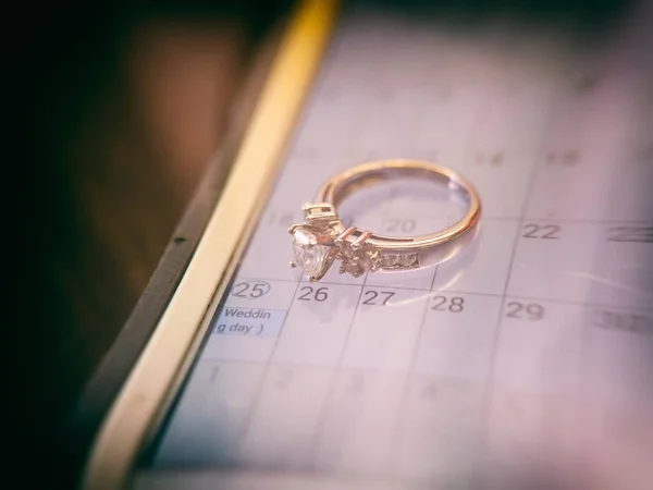Bague de mariage dorée avec un diamant et une date de mariage entourée sur le calendrier — Photo