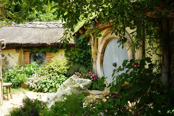 Prachtig shot van een klein houten huisje in de tuin omgeven door bloemen en weelderige natuur — Stockfoto
