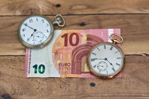 Hoge hoek opname van twee vintage klokken op een tien Euro op een houten tafel — Stockfoto