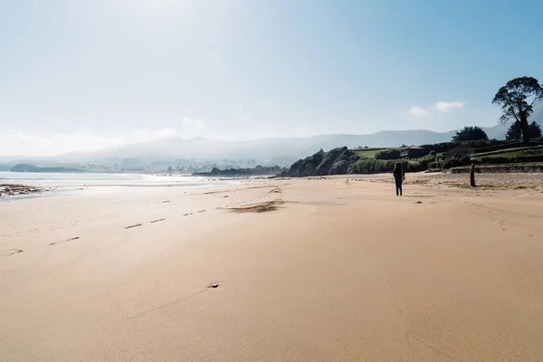 Hinter der Aufnahme einer Frau, die am Strand Sand in Küstennähe läuft, mit Bergen im Hintergrund — Stockfoto