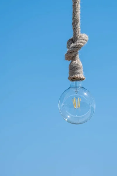 青の背景にロープからぶら下がっている電球の垂直ショット — ストック写真