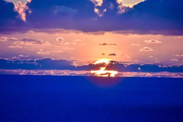 Décor du coucher de soleil dans l'océan avec un ciel nuageux violet — Photo
