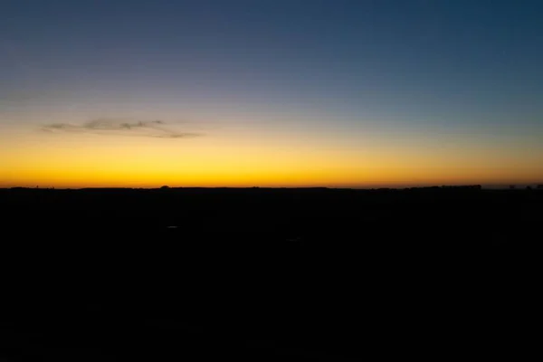 Vista hipnotizante da silhueta dos campos durante o pôr do sol com um céu colorido — Fotografia de Stock