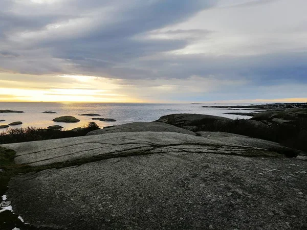 Moře obklopeno skálami pod zataženou oblohou během západu slunce v Rakke v Norsku — Stock fotografie