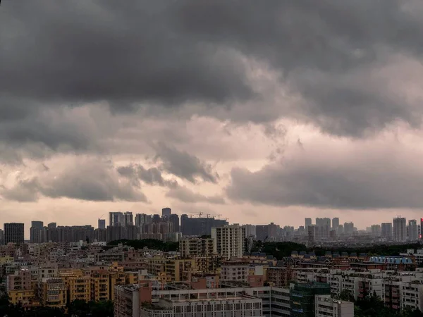 Vista para uma cidade moderna e movimentada com céu cinzento escuro e nuvens — Fotografia de Stock