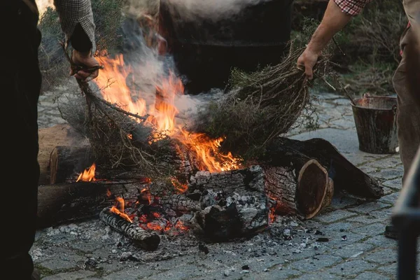 Cierre de las personas que hacen un fuego de hoguera rodeado de leña y vegetación en un parque. — Foto de Stock