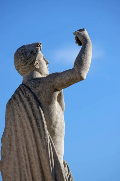 Socha muže, který hrdě drží ruku ve vzduchu pod jasnou modrou oblohou — Stock fotografie