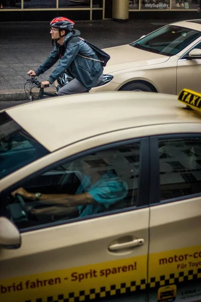 一个骑自行车的人坐在出租车旁边的垂直镜头 — 图库照片