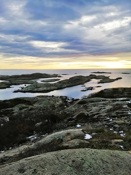 Vertikal bild av klippor omgivna av havet under solnedgången i Rakke i Norge — Stockfoto
