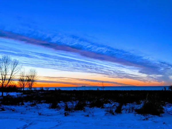 Pôr-do-sol durante o inverno com o chão coberto de neve — Fotografia de Stock